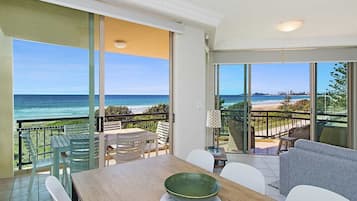 Enjoy the ocean view from this room's expansive balcony, featuring a table, chairs, and a wicker chair.