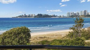 Un paysage urbain côtier avec une plage au premier plan et une rangée d’immeubles de grande hauteur en arrière-plan.