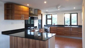 A modern kitchen with wooden cabinets, a black countertop, and a built-in washing machine.
