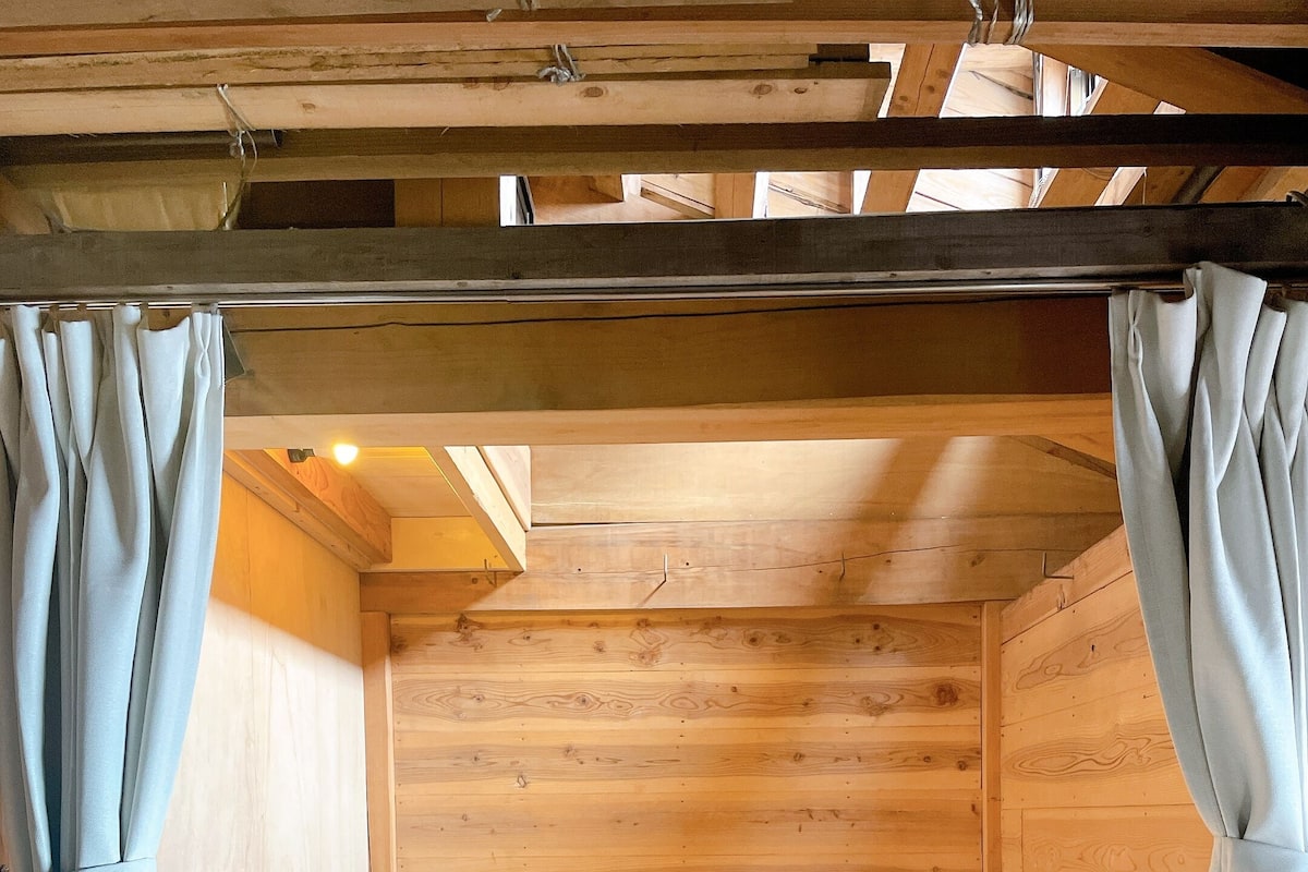 A wooden cabin with two bunk beds, each with a number tag, and curtains on the sides.