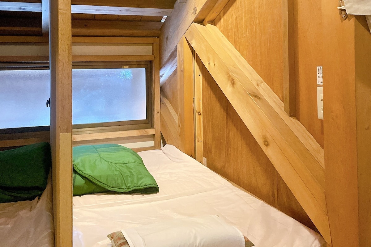 A small, wooden room with a bunk bed, a window, and a door.