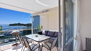 A balcony with a table and chairs, a view of the sea, and a sign that reads "LIFE'S A BEACH". - Laman Lodge, 6,15 Laman Street - Air Conditioned unit with spectacular views and free Wi-Fi (Nelson Bay)