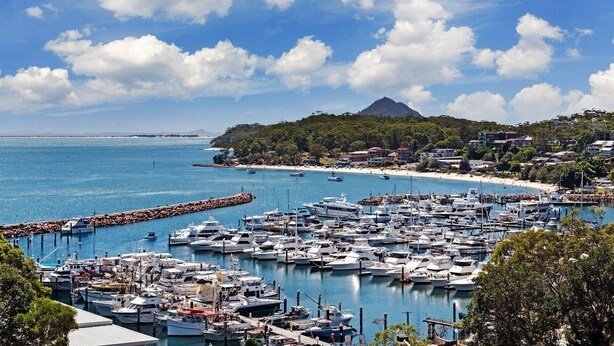 A marina with numerous boats docked, a sandy beach, and a mountain in the background. - Laman Lodge, 6,15 Laman Street - Air Conditioned unit with spectacular views and free Wi-Fi (Nelson Bay)