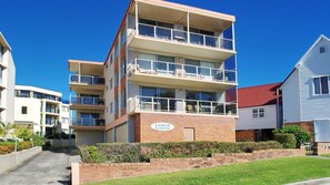 A multi-story LAMAN LODGE building with balconies, a brick facade, and a clear blue sky.