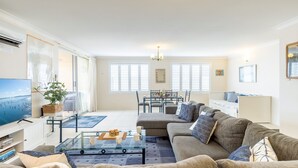 A spacious living room with a sofa, coffee table, TV, and dining area. - Laman Lodge, 6,15 Laman Street - Air Conditioned unit with spectacular views and free Wi-Fi (Nelson Bay)