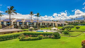 Un hotel de varios pisos, con paneles solares en los tejados, piscina y jardines bien cuidados.