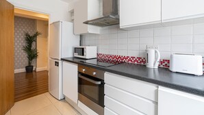 A modern kitchen with white cabinets, a stainless steel oven, a microwave, a toaster, and a red and white tiled backsplash. - Nice 3 Bedrooms Apartment Near Hyde Park & Oxford St (London)