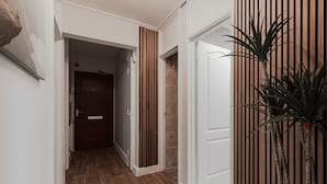 A hallway with wooden flooring, a door, and a potted plant. - Lovely Apartments in Landward Court (London)