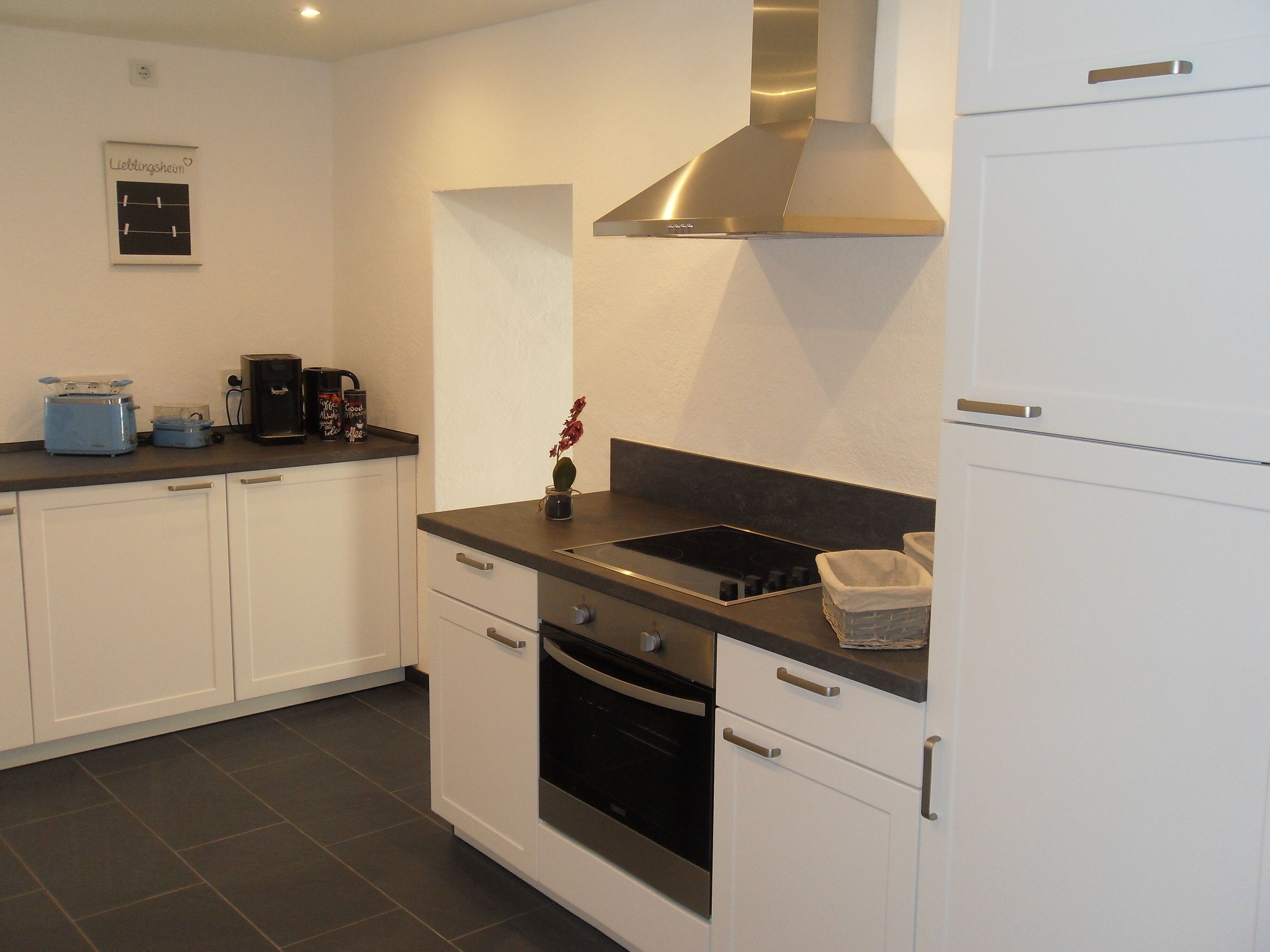 A modern kitchen with white cabinets, a black stove, and a stainless steel range hood.