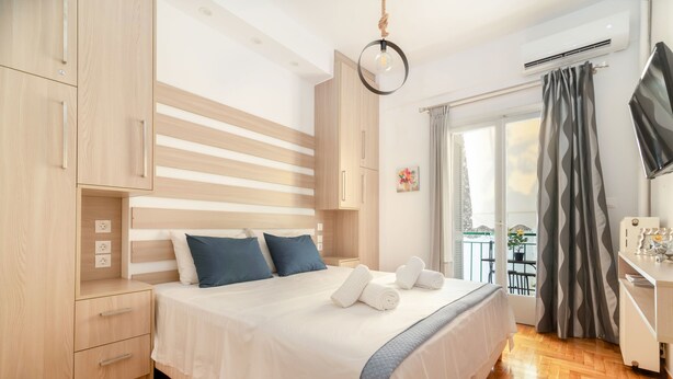 A modern bedroom with a large bed, wooden wardrobe, and a balcony with a view. - Apartment Hermes in Central Athens (Athens)