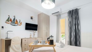 A modern bedroom with a bed, bedside table, TV, and a view of the outdoors. - Apartment Hermes in Central Athens (Athens)