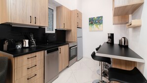 A modern kitchen with wooden cabinets, a black countertop, a dishwasher, an oven, and a coffee machine. - Apartment Hermes in Central Athens (Athens)