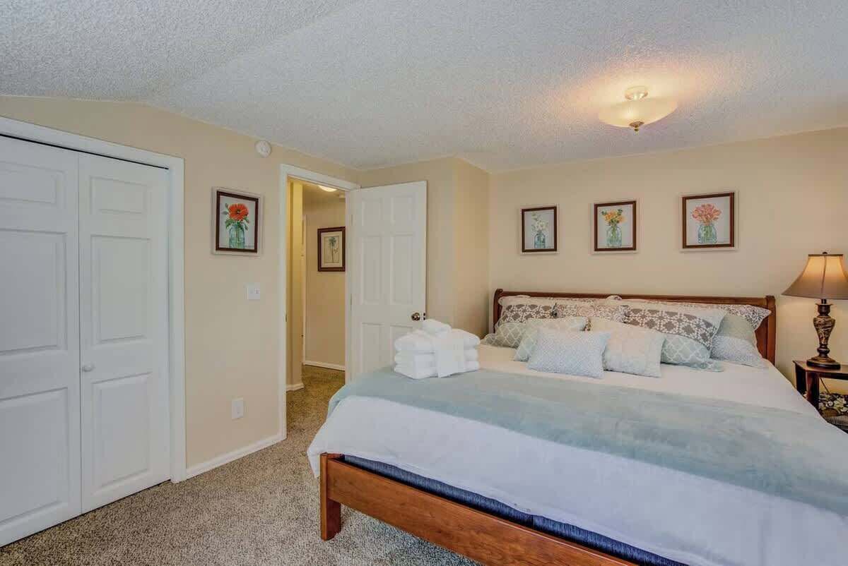 Un dormitorio con una cama, una mesita de noche, una lámpara y cuadros en la pared.