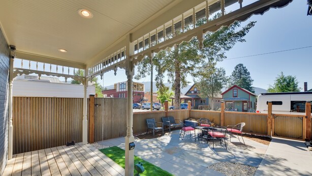 Un patio cubierto con piso de madera, mobiliario exterior y vistas a casas vecinas.