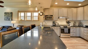 Una cocina moderna con una isla grande, armarios de madera, electrodomésticos de acero inoxidable e iluminación colgante.