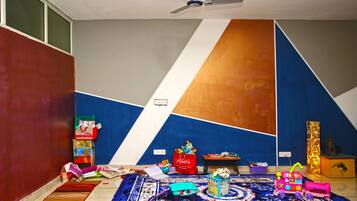Cozy space for kids, featuring a geometric wall design, a ceiling fan, and a play area with toys and books.