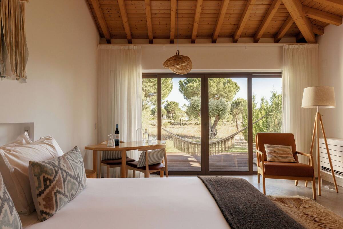 A bedroom with a large bed, a wooden desk, a chair, and a hammock.