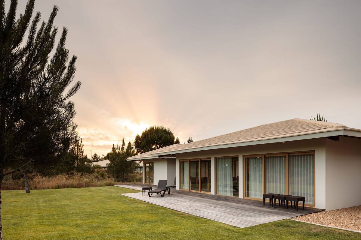 A modern house with a flat roof, large sliding glass doors, and a wooden deck.
