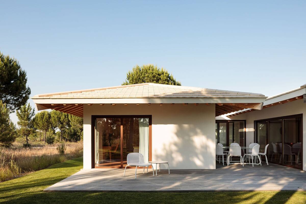 A modern house with a patio, large sliding glass doors, and a small outdoor seating area.