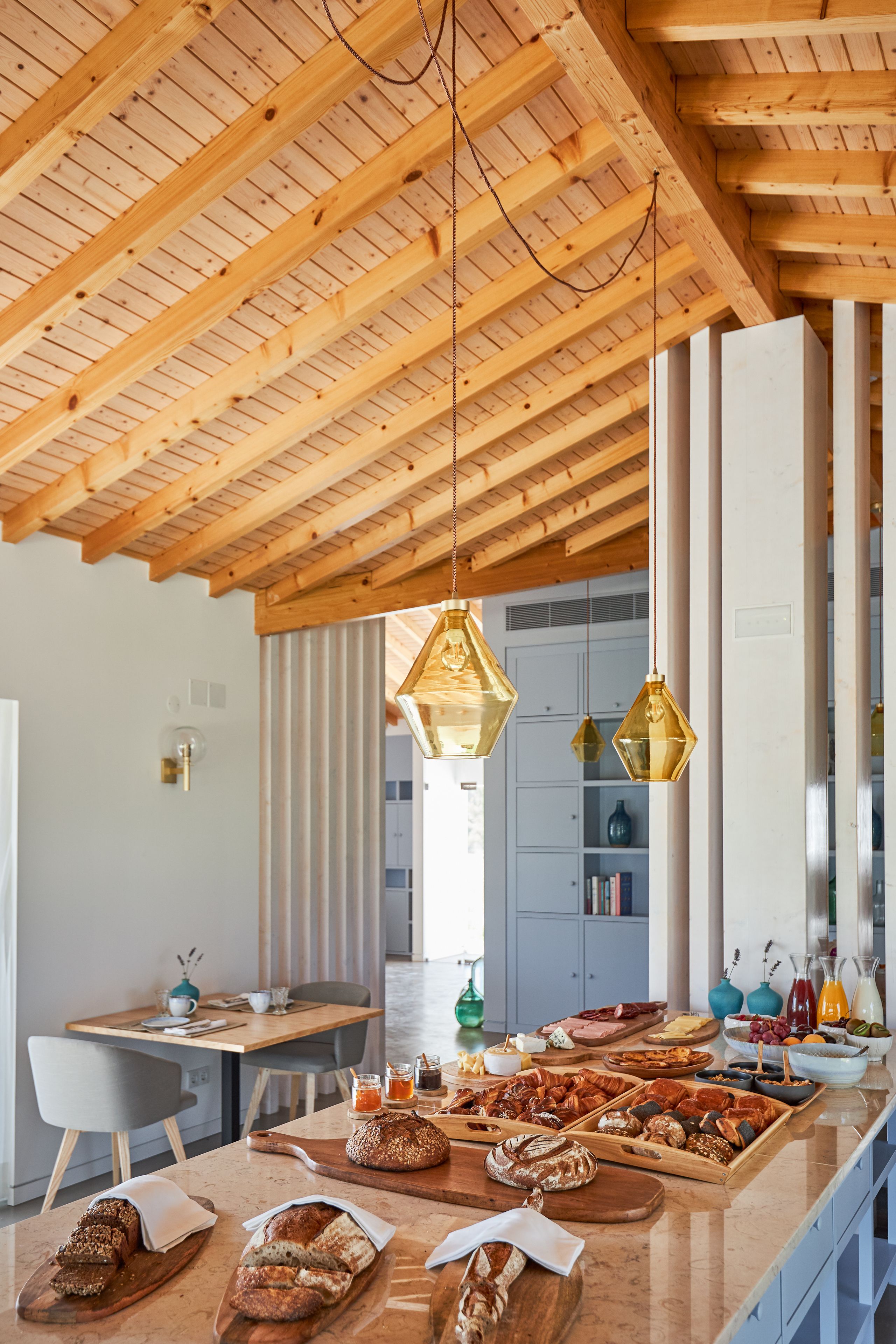 A spacious kitchen with wooden beams, a marble countertop, and a variety of breakfast items.