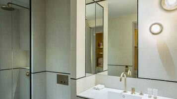 Un baño moderno con un espejo grande, un lavabo blanco y una ducha.