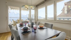 Comedor con una mesa dispuesta para seis comensales, ventanas amplias con vista a la montaña y un balcón con mobiliario exterior.