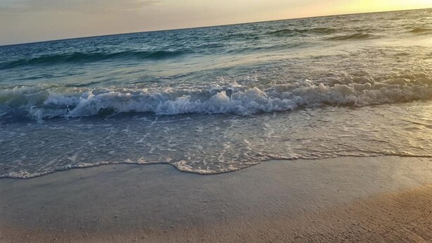 A beach with waves approaching the shore.