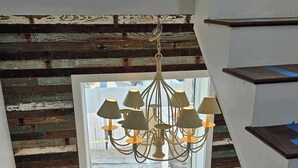 A staircase with a rustic wooden wall and a chandelier.