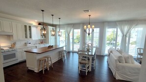 A spacious kitchen with white cabinetry, a central island with stools, and pendant lighting.
