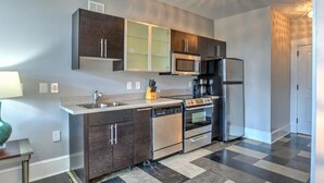 A modern kitchen with dark cabinets, a microwave, a refrigerator, a dishwasher, and a stove. - Charming Historic King James Building Unit #3 (Asheville)