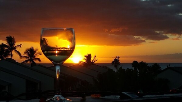A sunset view with palm trees and a glass of wine on a balcony. - Hale Kamaole 328 Third floor condo, easy access to best beach on Maui! (Kihei)