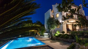 Ein modernes Gebäude mit Pool, umgeben von üppiger Vegetation und einem gut beleuchteten Außenbereich.