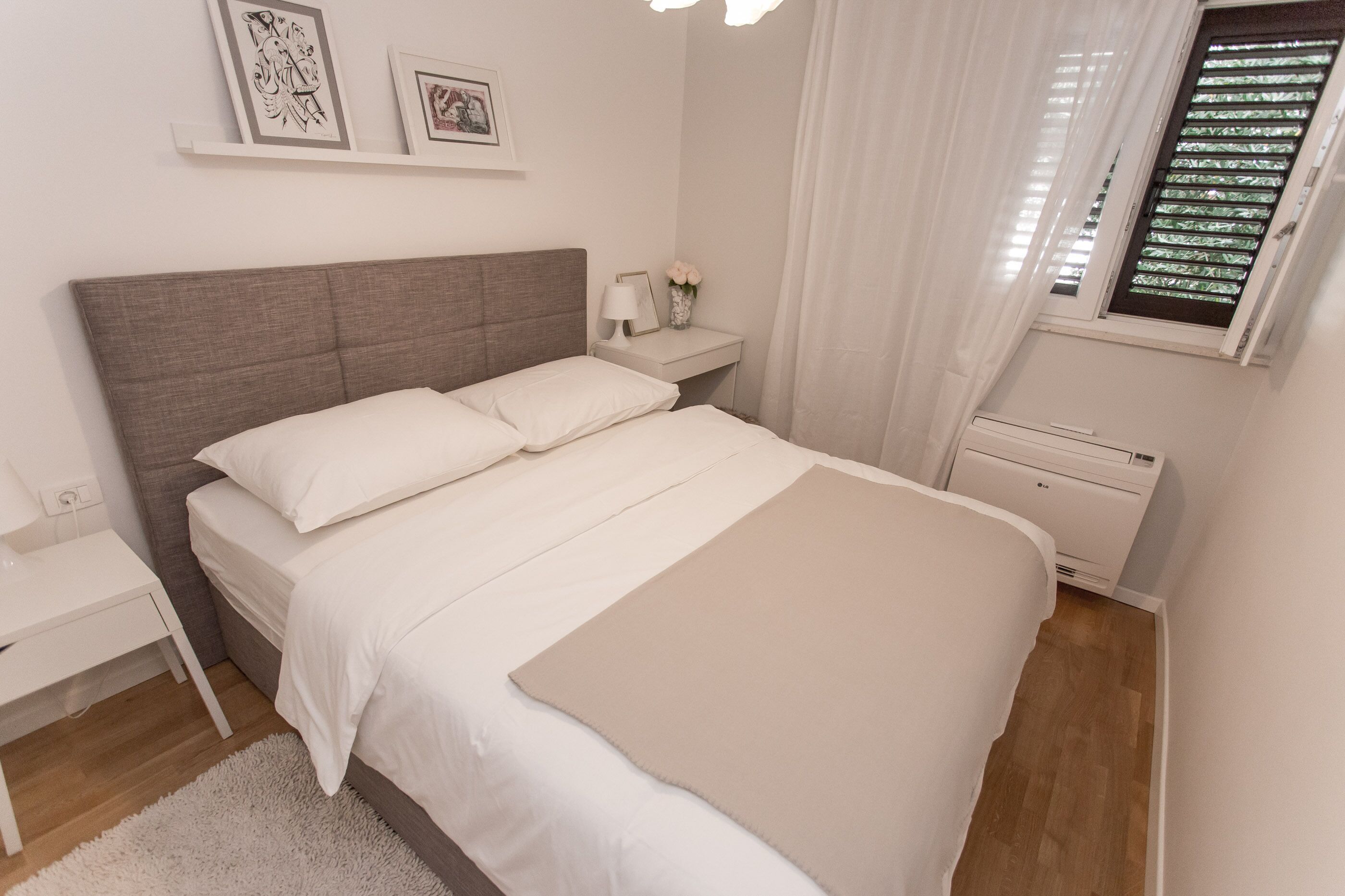 Une chambre bien rangée, avec un lit, une table de chevet et un petit bureau.