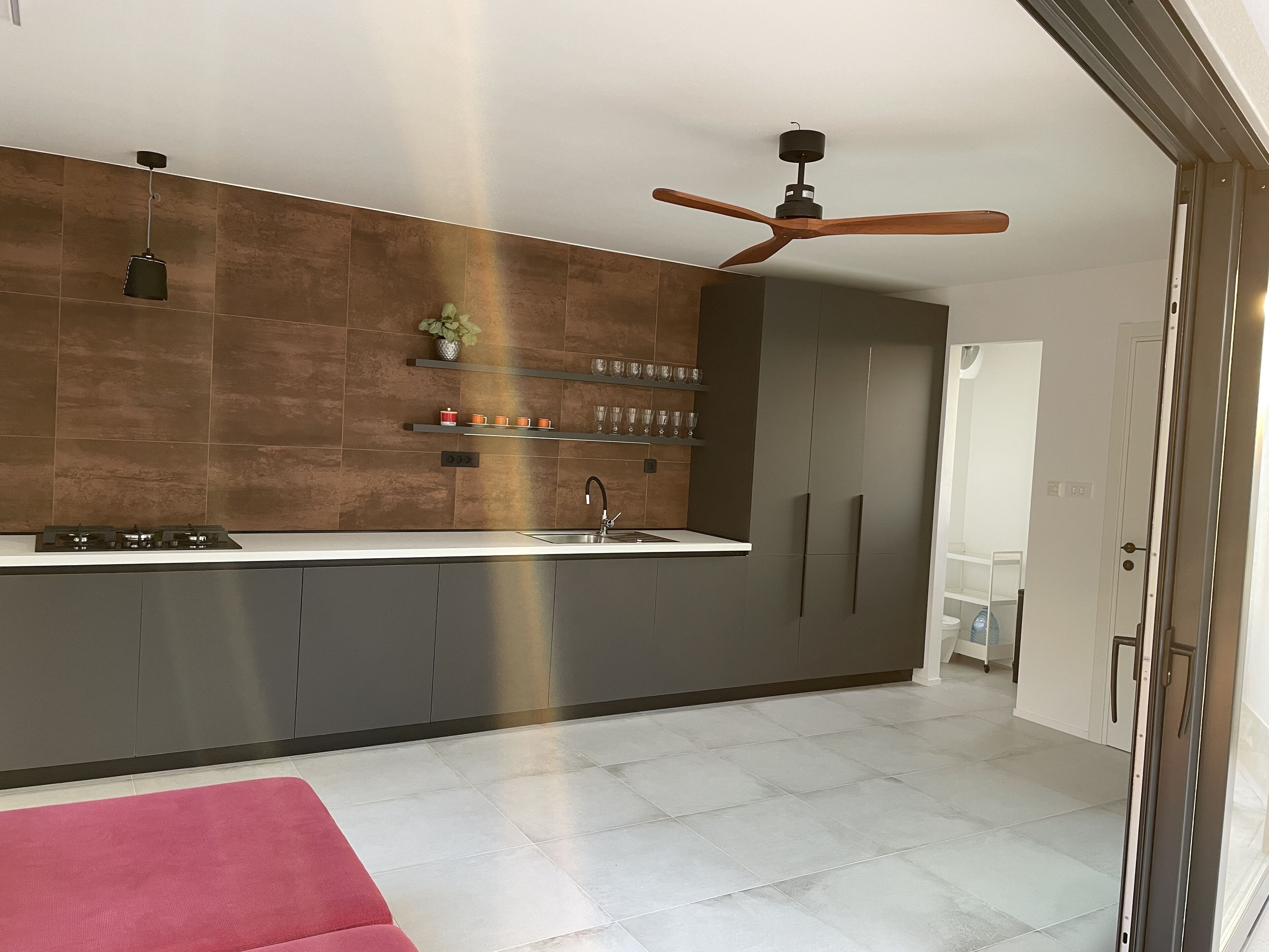 A modern kitchen with a built-in gas stove, a ceiling fan, and a sink.