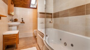 Un baño con techo de madera, una bañera, un lavamanos y un inodoro.