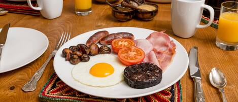 A breakfast plate with eggs, sausages, tomatoes, and ham.