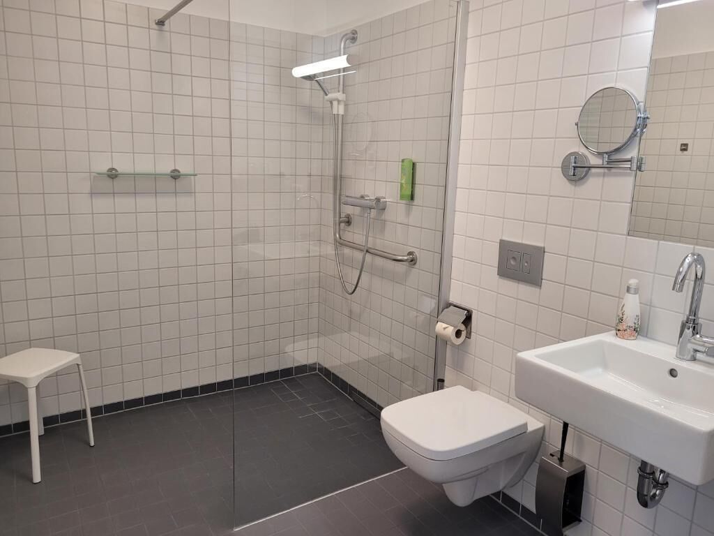 Uma casa de banho moderna com chuveiro, sanita e lavatório.