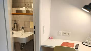 A compact kitchenette with a sink, a countertop, and a chair.