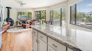 A spacious living area with a fireplace, comfortable seating, a dining table, and large windows offering a view of the outdoors. - The Treehouse on Lake Travis (Lakeway)