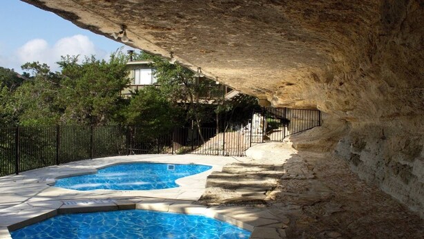 An outdoor swimming pool with a stone pathway leading to a staircase. - The Treehouse on Lake Travis (Lakeway)