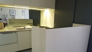 Uma cozinha moderna com armários brancos, uma pia de aço inoxidável e um fogão a gás.