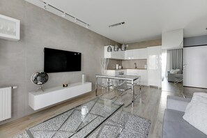 A modern living room with a glass coffee table, a flat-screen TV mounted on the wall, and a minimalist design. - NORDBYHUS Apartamenty Angielska Grobla (Gdansk)