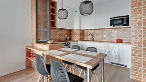 Una cocina compacta con una mesa de madera, cuatro sillas, microondas y un salpicadero de ladrillo.