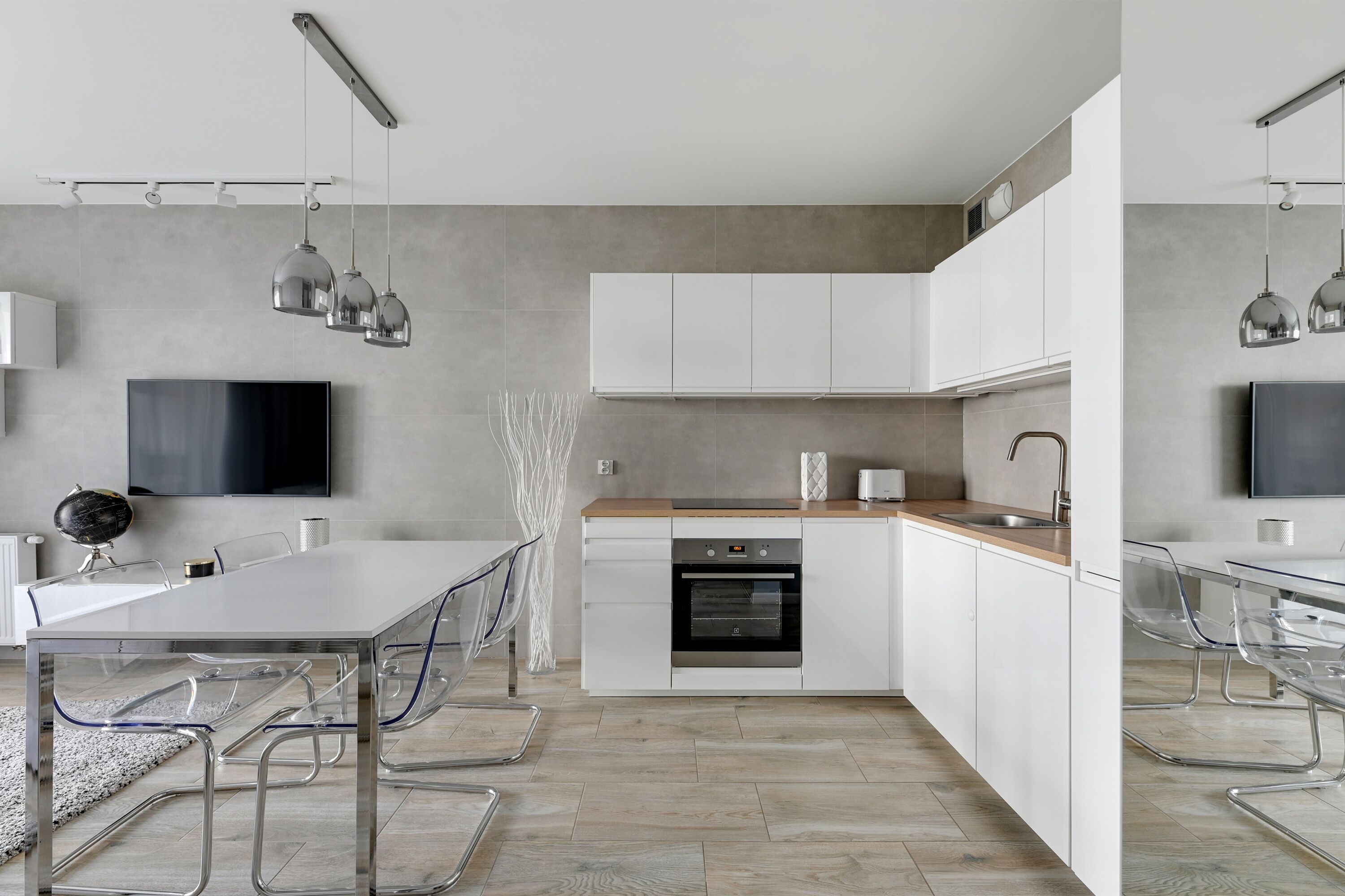 A modern kitchen with a central island, white cabinetry, and a built-in oven.