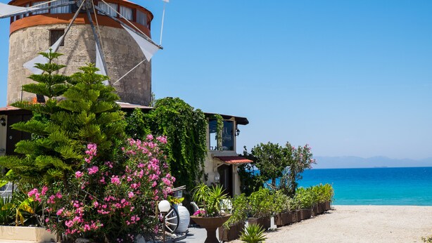A windmill, a building with a red roof, and a view of the sea. - Windmill Tower Beach House in Rhodes island (Ialisos)