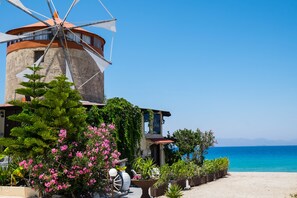 A windmill, a building with a red roof, and a view of the sea.