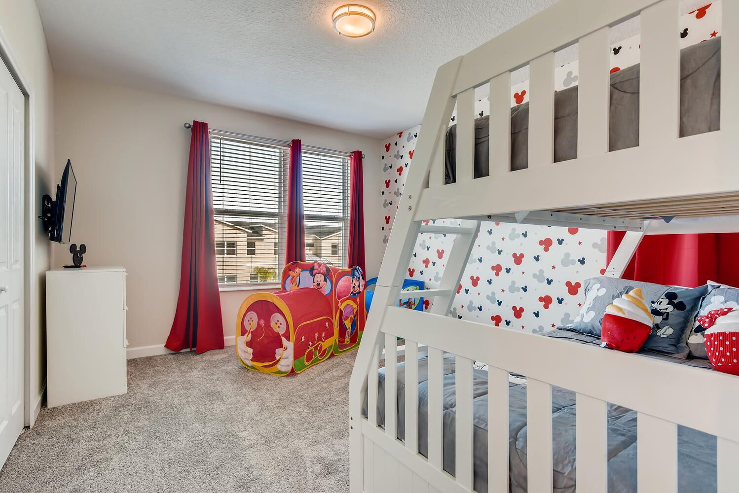 A child's room with bunk beds, a playhouse, and Mickey Mouse-themed decor.