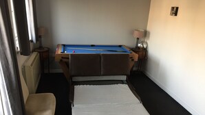 Una habitación con una mesa de billar, una cama, una silla y dos lámparas.