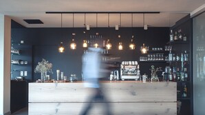 A modern bar area with wooden counters, hanging light fixtures, and shelves stocked with bottles and glasses. - Das Wanda (Caldaro Sulla Strada del Vino)