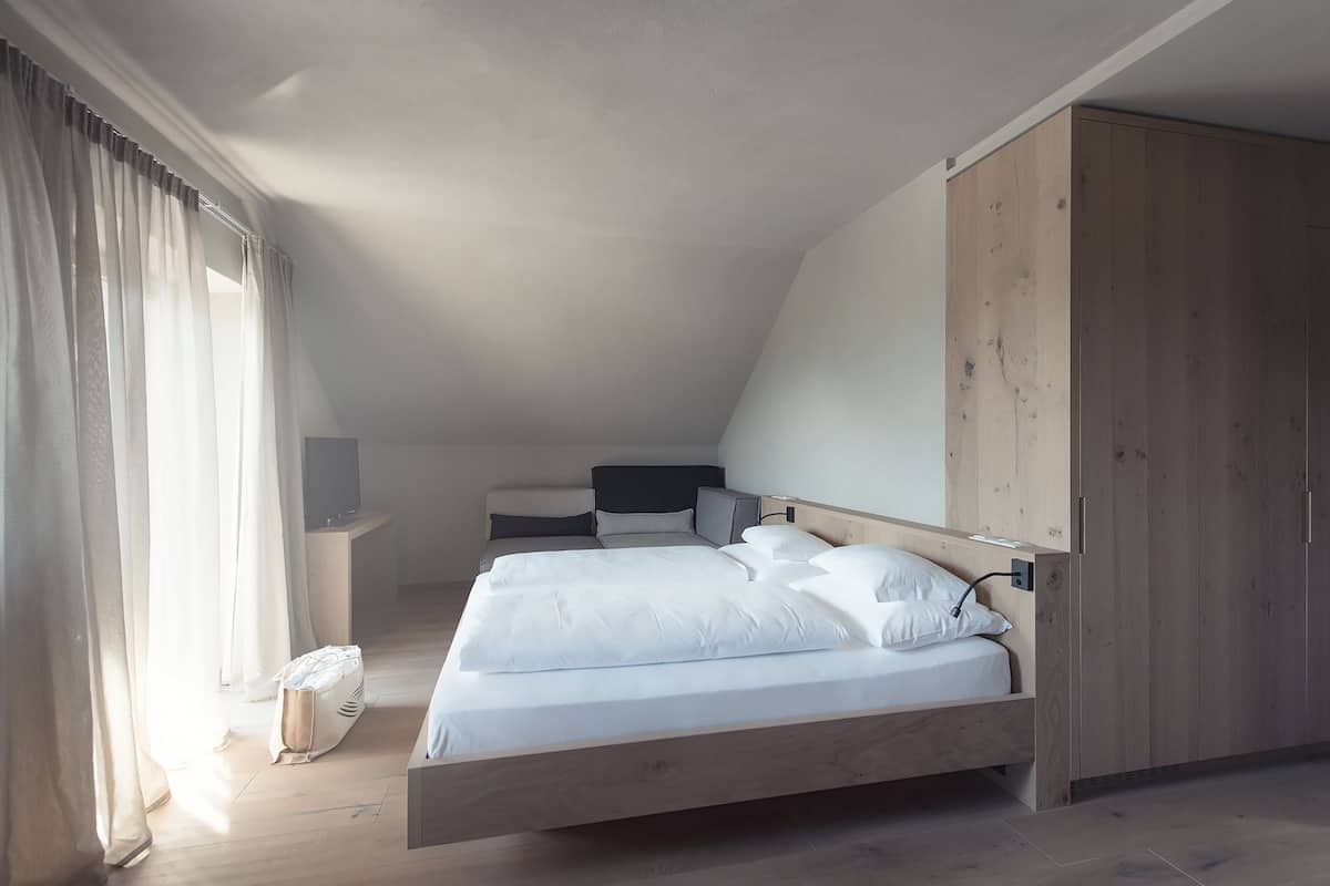 A bedroom with a bed, a wardrobe, a bedside table, and a TV.